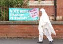 A woman walks past a sign for a polling station location in Rochdale, Greater Manchester