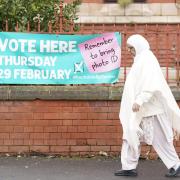 A woman walks past a sign for a polling station location in Rochdale, Greater Manchester