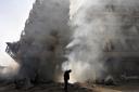 A man walks in front of a burning building after a Syrian Air force air strike in Ain Tarma neighbourhood of Damascus in this January 27, 2013 file photo.  REUTERS/Goran Tomasevic/Files