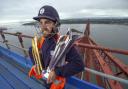 Preston Mommsen, the Scotland captain, clings on to the World T20 and World T20 Qualifier trophy atop the Forth Rail Bridge. Picture: Donald MacLeod/Cricket Scotland