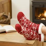 Woman in Christmas socks relaxing next to a wood burning stove.