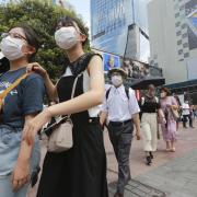 People wearing face masks to protect against the spread of the coronavirus walk on a street in Tokyo Wednesday, July 28, 2021.  (AP Photo/Koji Sasahara).