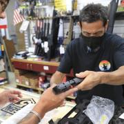A clerk hands a gun to a customer inside a gun shop, Thursday, June, 23, 2022 in Honolulu. In a major expansion of gun rights after a series of mass shootings, the Supreme Court said Thursday that Americans have a right to carry firearms in public for