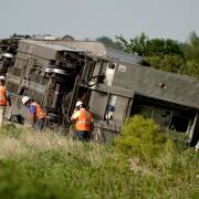 Workers inspect the scene of an Amtrak train which derailed after striking a dump truck Monday, June 27, 2022, near Mendon, Mo. (AP Photo/Charlie Riedel)