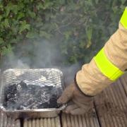 A disposable barbecue is attended to by a member of the fire service