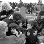 Frightened mourners take shelter behind gravestones in Milltown Cemetery, Belfast, on March 16, 1988 during the bloody assault by Michael Stone