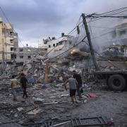 Palestinians walk amid the rubble following Israeli airstrikes that razed swaths of a neighborhood