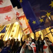 Protesters wave Georgian national and European flags during a demonstration outside the parliament building as they protest against a draft bill on 
