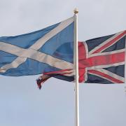 A Saltire flag and a Union flag flying above Whitehall in Westminster, London. Photo PA.