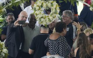 FIFA President Gianni Infantino, left, takes a selfie with Lima, a former Santos soccer player, and others, during the wake of the late Brazilian soccer great Pelé, who lies in state, at Vila Belmiro stadium in Santos, Brazil