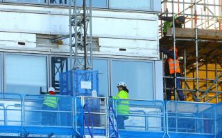 Workmen remove the cladding from the facade of a block of flats