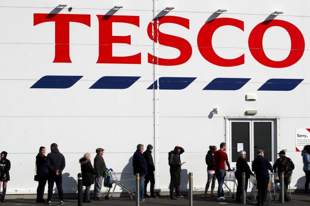 HeraldScotland: People queue outside a Tesco Extra store in Madeley, Shropshire