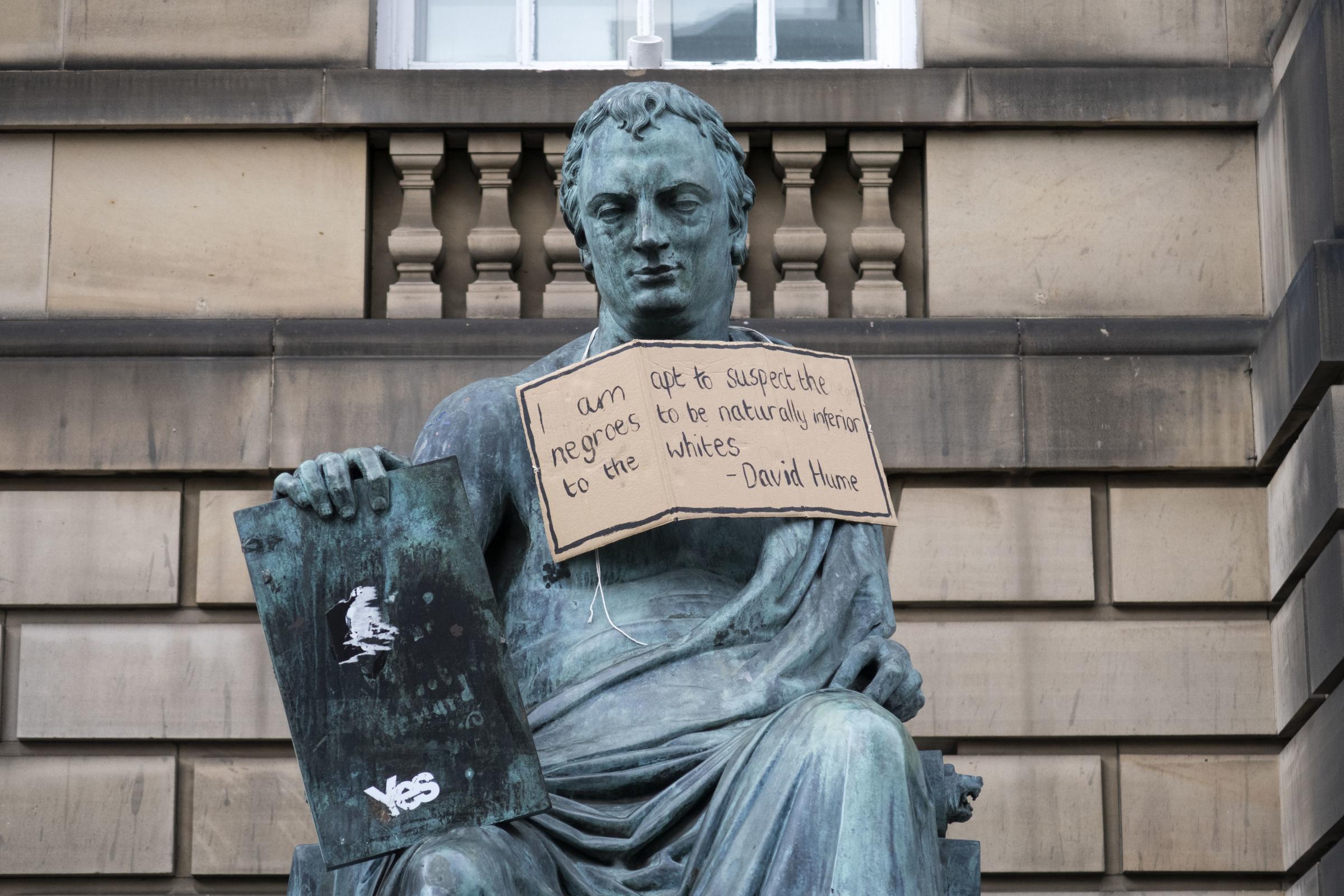 A placard hangs on the statue of 18th-century philosopher David Hume on Edinburgh's Royal Mile following the Black Lives Matter protest rally at Holyrood Park in Edinburgh on June 7, 2020 in memory of George Floyd, who died on 25 May May was killed during