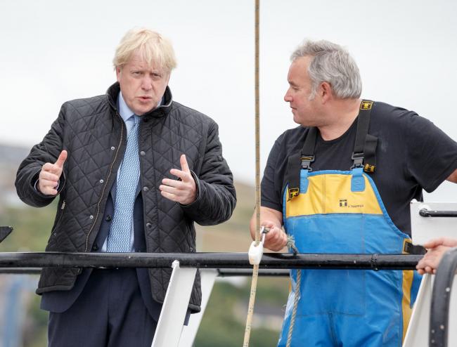 STROMNESS, SCOTLAND - JULY 23: British Prime Minister Boris Johnson chats to Ronnie Norquoy, owner of Celtic Dawn Fishing as crabs caught on the Carvela are brought in, at Stromness Harbour on July 23, 2020 in Stromness, Scotland. This week marks one year