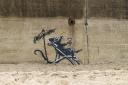One of the new works by Banksy, depicting a rat reclining in a deckchair drinking a cocktail under an umbrella, was painted on a beach wall at Lowestoft in Suffolk. Picture: Banksy/PA Wire