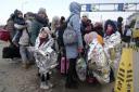 Refugees stand in a group after fleeing the war from neighbouring Ukraine at the border crossing in Palanca, Moldova, Thursday, March 10, 2022. (AP Photo/Sergei Grits)