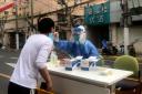 A medical worker conducts Covid tests for residents in Shanghai (Chen Si/AP)