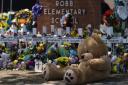 A large teddy bear is placed at a memorial in front of crosses bearing the names of the victims killed in this week's school shooting in Uvalde, Texas Saturday, May 28, 2022. (AP Photo/Jae C. Hong).