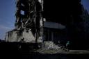 A woman walks past a building destroyed in Russian shelling in Borodyanka, on the outskirts of Kyiv, Ukraine, Tuesday, June 21, 2022. (AP Photo/Natacha Pisarenko).