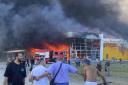People watch as smoke bellows after a Russian missile strike hit a crowded shopping mall, in Kremenchuk, Ukraine, Monday, June 27, 2022. Ukrainian officials say scores of civilians are feared killed or injured after a Russian missile strike hit a crowded