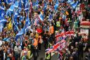 A handful of anti-independence supporters wave Union flags as tens of thousands of demonstrators march in support of independence through the streets of Glasgow