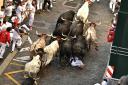 A runner falls as people run through the street with fighting bulls at the San Fermin Festival in Pamplona, northern Spain, Friday, July 8, 2022. Revellers from around the world flock to the city every year for nine days of uninterrupted partying in