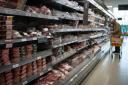 A shopper walks through the fresh meat aisle in a branch of Waitrose in south London