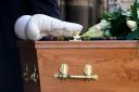 A pair of white boxing gloves rest on the coffin of former boxer Ken Buchanan