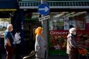 Shoppers wearing face masks observe social distancing as they queued for a shop in east London during the pandemic (Victoria Jones/PA)
