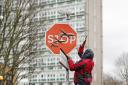 People remove a piece of art work by Banksy, which shows what looks like three drones on a traffic stop sign, which was unveiled at the intersection of Southampton Way and Commercial Way in Peckham, south east London
