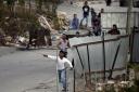 Palestinian protesters, in the West Bank village of Sair, hurl rocks at Israeli soldiers in the Beit Einun junction east of the West Bank town of Hebron on October 26, 2015, after Palestinian Raed Jarradat, had stabbed and seriously wounded an Israeli bef
