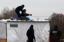 CALAIS, FRANCE - MARCH 01:  A woman threatens to cut her wrist with a knife as French police remove her and a man from the top of a hut as they clear the "jungle" migrant camp on March 01, 2016 in Calais, France. Police and demolition teams are 