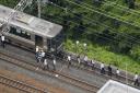 Passengers walk on railroad as the train service was suspended following an earthquake in Takatsuki, Osaka.