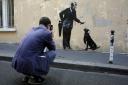 A man takes a picture of a graffiti believed to be attributed to street artist Banksy, in Paris, Monday, June 25, 2018. Seven works attributed to the graffiti artist have been discovered in recent days, including one near a former center for migrants at t