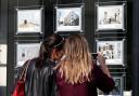 Buyers study the house price signs in an estate agents window