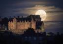 The full moon rises behind Edinburgh Castle. Credit: PA