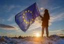 A young girl holds the flag of the European Union as she looks towards Whitelee Wind Farm outside Glasgow. Photo Colin Mearns.