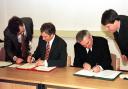 Tony Blair (left) signs the Good Friday agreement with George Fergusson at his shoulder and Irish Taoiseach, Bertie Ahern on his right