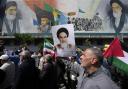 Iranian worshippers walk past a mural showing the late revolutionary founder Ayatollah Khomeini