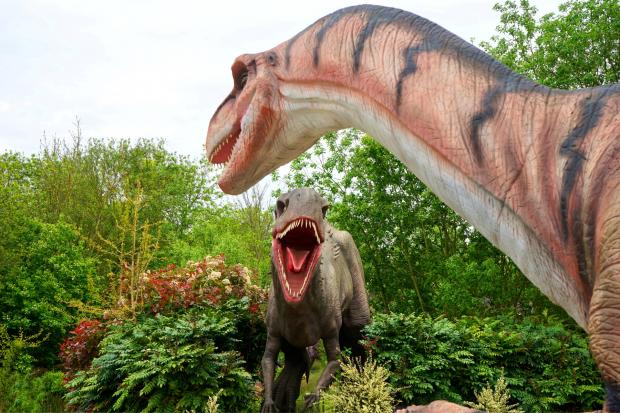 HeraldScotland: Two dinosaurs facing off in the woodland. Credit: Canva