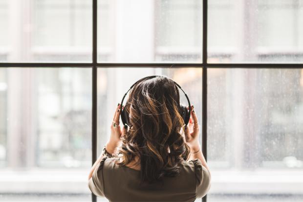 HeraldScotland: A woman listening to music on her headphones. Credit: Canva
