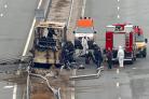 Firefighters and forensic workers inspect the scene of a bus crash on a highway near the village of Bosnek, western Bulgaria, Tuesday, Nov. 23, 2021. A bus carrying tourists back to North Macedonia crashed and caught fire in western Bulgaria early
