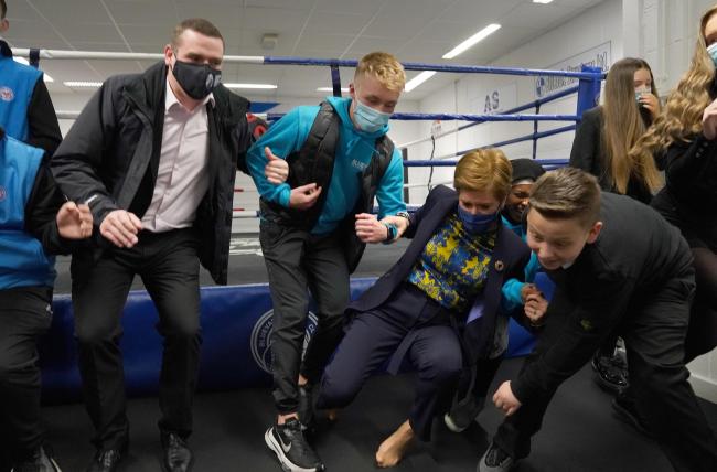 First Minister Nicola Sturgeon falls to the ground after jumping from a boxing ring along with Scottish Conservative leader Douglas Ross during a visit to a drugs support group at the Bluevale Community Club in Glasgow