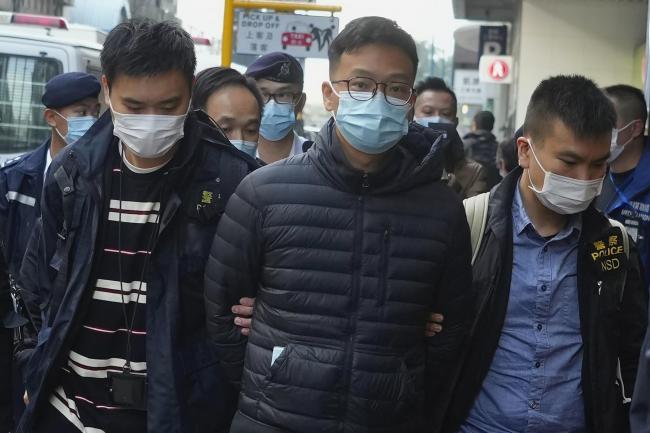 Editor of Stand News Patrick Lam, centre, is arrested by police officers in Hong Kong, Wednesday, Dec. 29, 2021. Hong Kong police say they have arrested several current and former staff members of the online media company for conspiracy to publish a