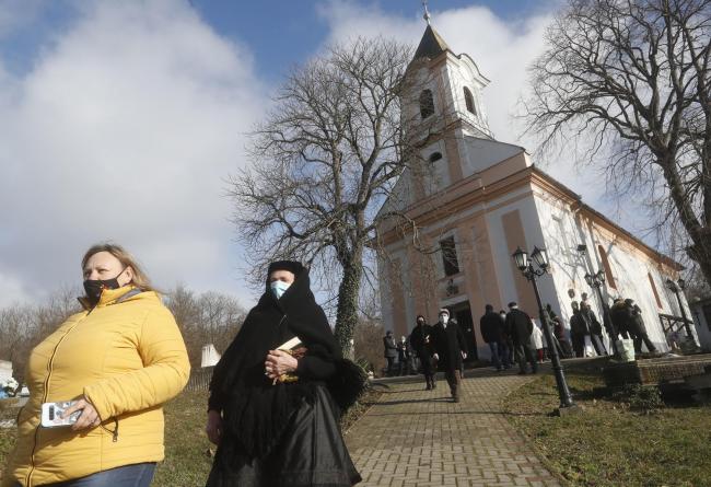 People, wearing masks for protection against the Covid-19 infection, stand outdoors during an outdoor Lutheran Church religious service in Csovar, Hungary, Sunday, Jan. 24, 2021.  (AP Photo/Laszlo Balogh).