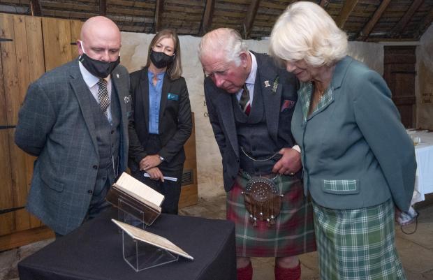 HeraldScotland: The Prince of Wales and the Duchess of Cornwall, known as the Duke and Duchess of Rothesay when in Scotland, take a look at the original manuscript of Auld Lang Syne during a visit to Robert Burns' Cottage in Alloway, South Ayrshire. Photo via PA/Jane Barlow.