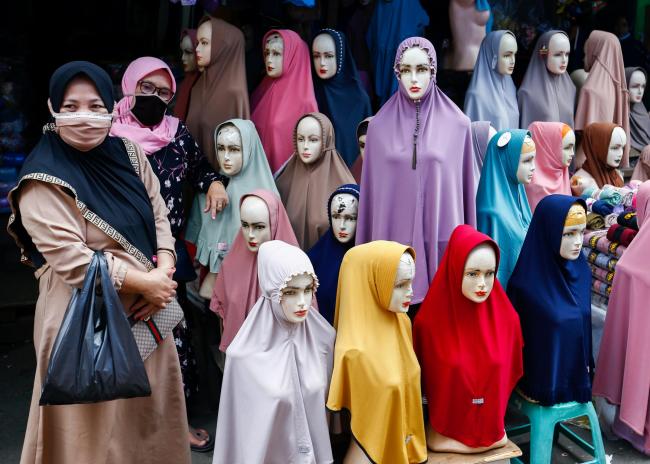 Women wearing protective masks stand next to hijabs for sale at the Tanah Abang textile market in Jakarta, Indonesia, in March 2021. (Ajeng Dinar Ulfiana/Reuters)