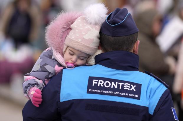 HeraldScotland: A guard carries a young child at the Slovakian border