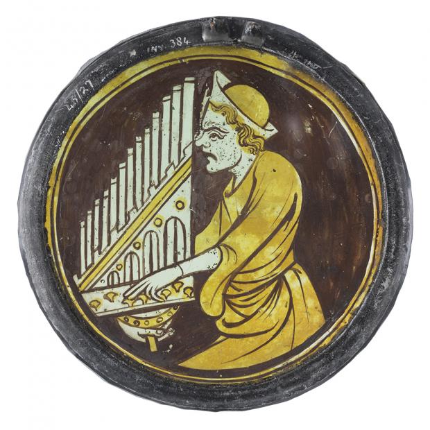 HeraldScotland: A stained-glass roundel, circa mid-1300s, depicting a man playing an organ. Picture: CSG CIC Glasgow Museums Collections