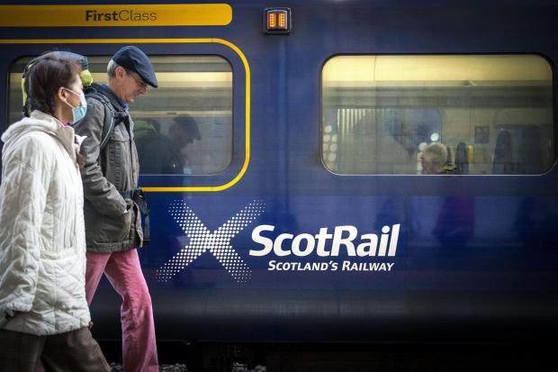 HeraldScotland: People walking past a ScotRail train